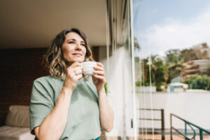 Contemplative mature woman looking throught the window at home